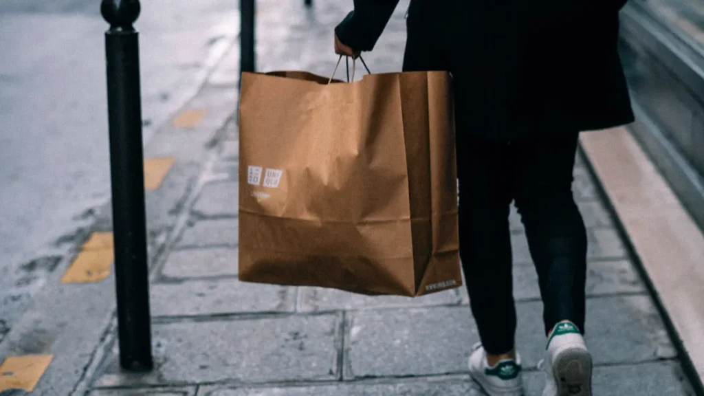ユニクロのショッピングバッグを持つ女性